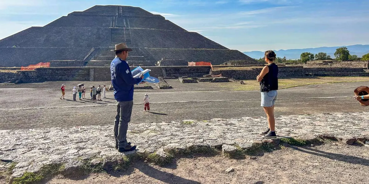 Guide talking with a visitor in front of the Pyramid of the Sun