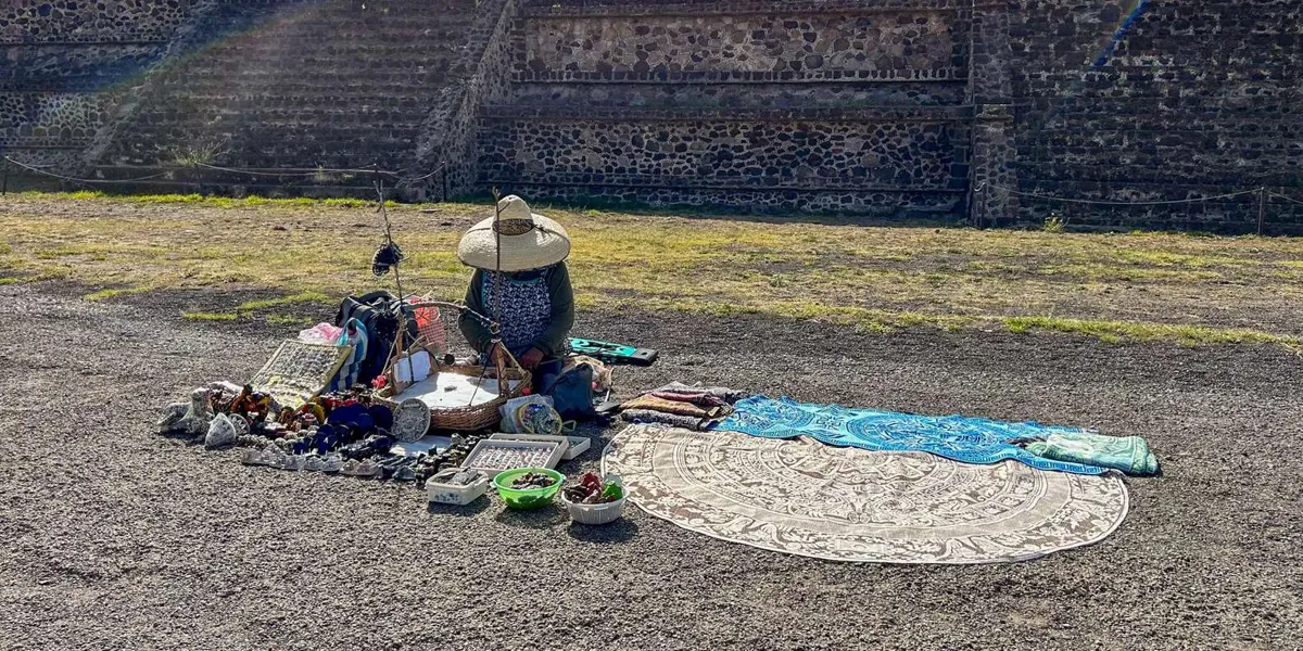 Craft seller seated with merchandise near a pyramid