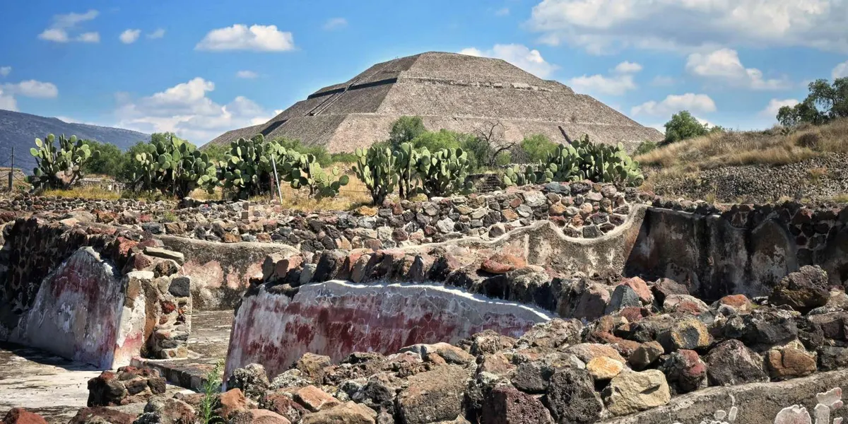 Pyramid seen beyond cactus plants and stone foundations